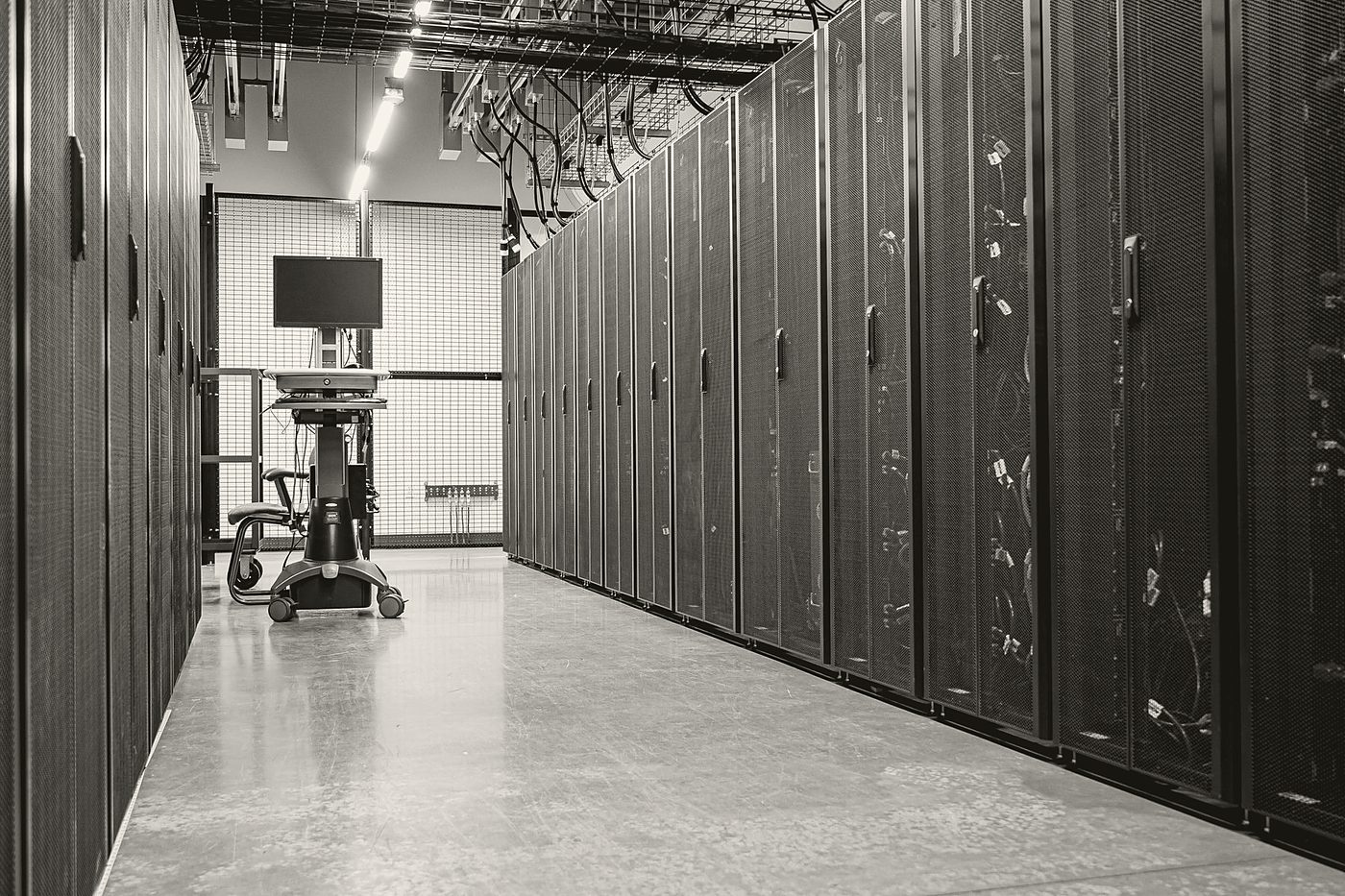 Black-and-white view down a data center aisle lined with server racks