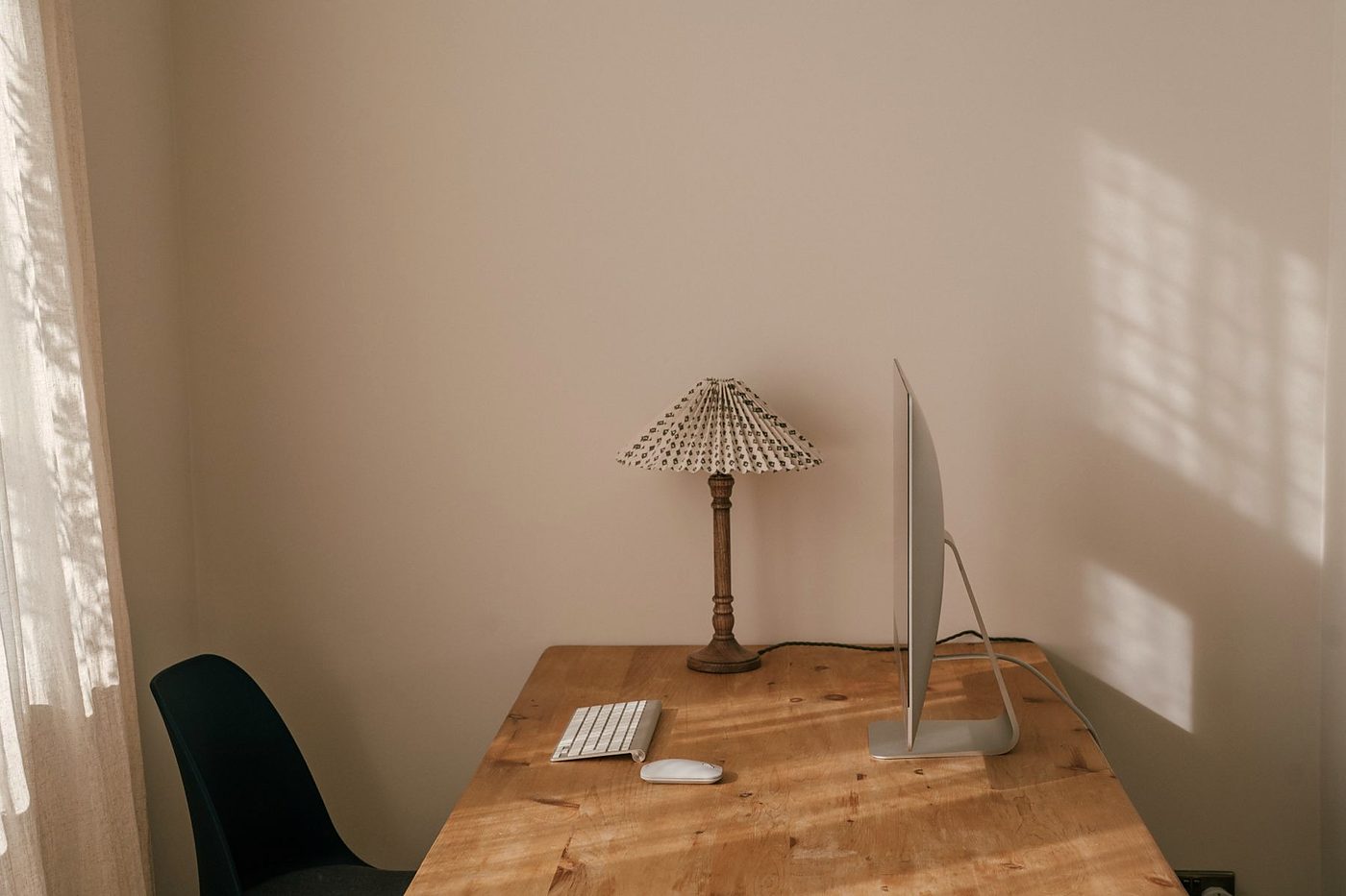 Minimal wooden desk with a computer monitor and warm window light